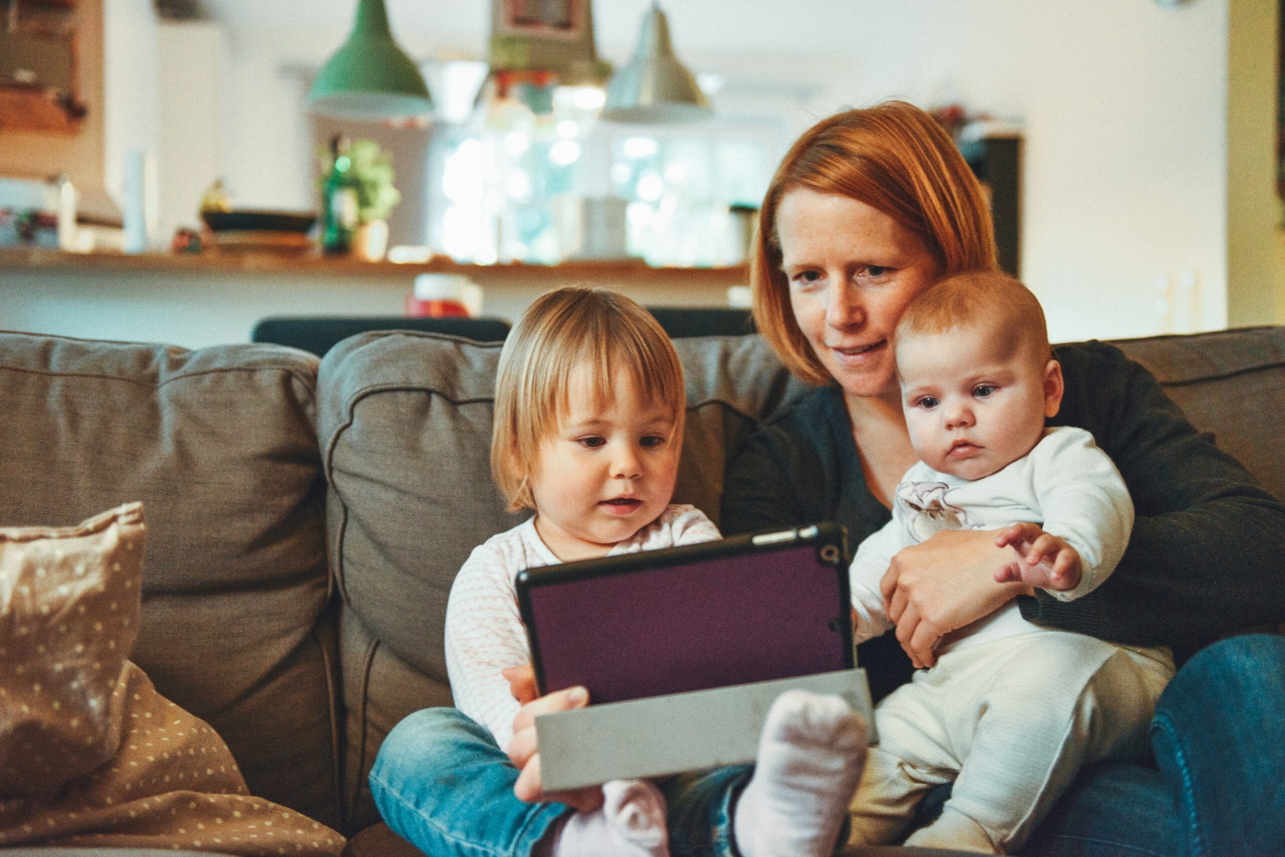 "Die Mutter schaut mit ihren zwei Kindern auf dem Tablet